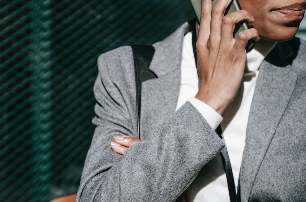 a woman in a gray suit is standing and talking on the phone