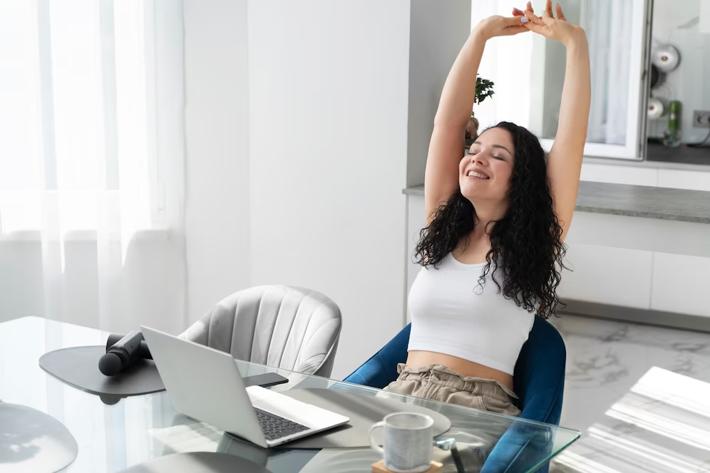 Woman raising her hand in a stretching motion in front of her laptop