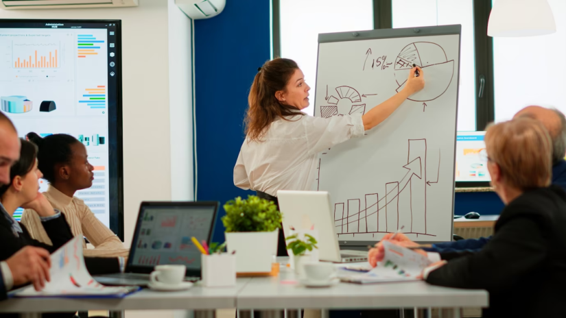 Group of employees having a meeting, with one person in the front illustrating graphs