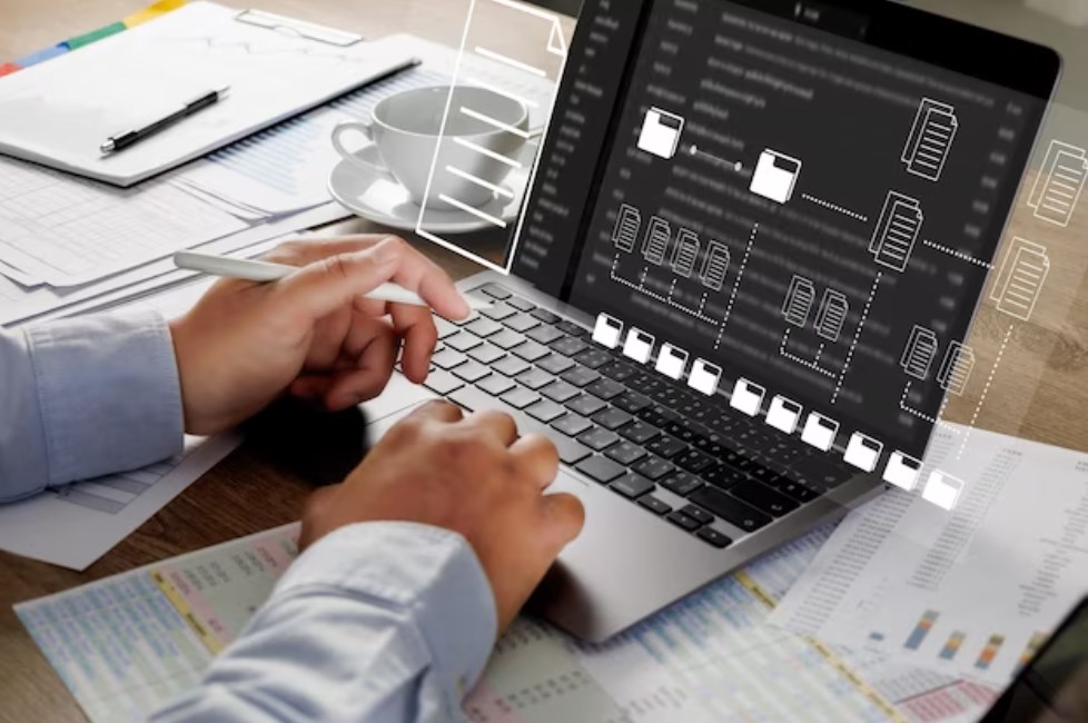 hands of a businessman sitting and signing a virtual contract with papers and a black laptop