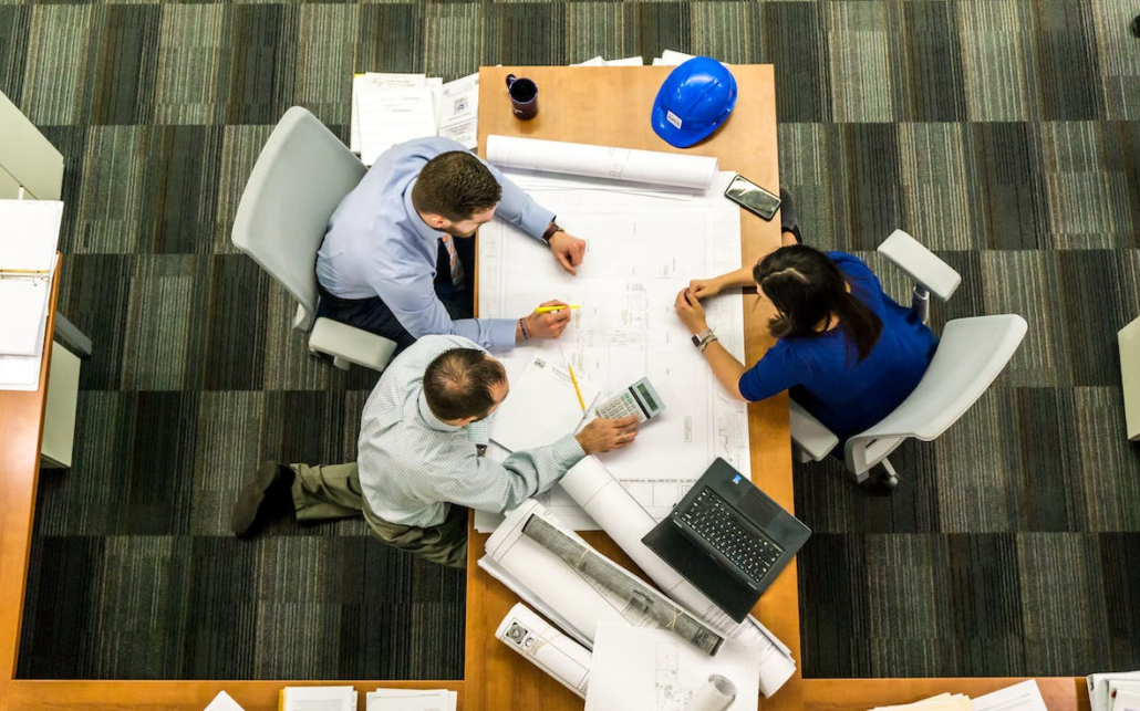 three colleagues are sitting in the office at work at the table, discussing work